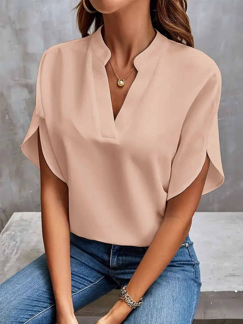 Blusa elegante da donna color pesca, maniche corte, scollo a V, abbinata a jeans. Moda casual chic, abbigliamento femminile estivo.