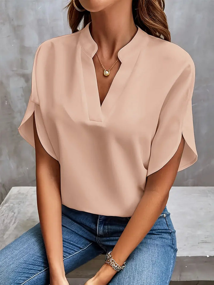 Blusa elegante da donna color pesca, maniche corte, scollo a V, abbinata a jeans. Moda casual chic, abbigliamento femminile estivo.