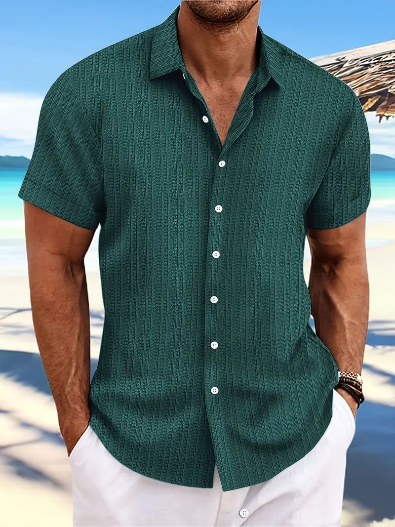 Camicia estiva da uomo verde a righe, maniche corte, sfondo spiaggia. Ideale per moda mare, look casual elegante.