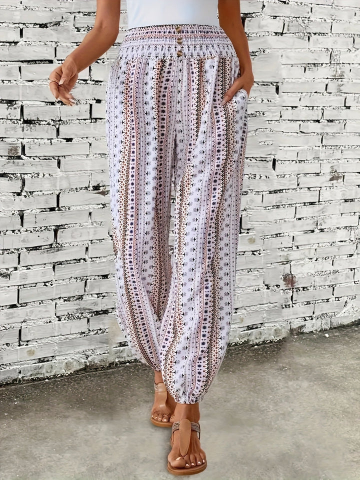 Pantaloni estivi donna a palazzo, bianchi con motivo geometrico nero, elastico in vita, tasche laterali, indossati con sandali marroni.
