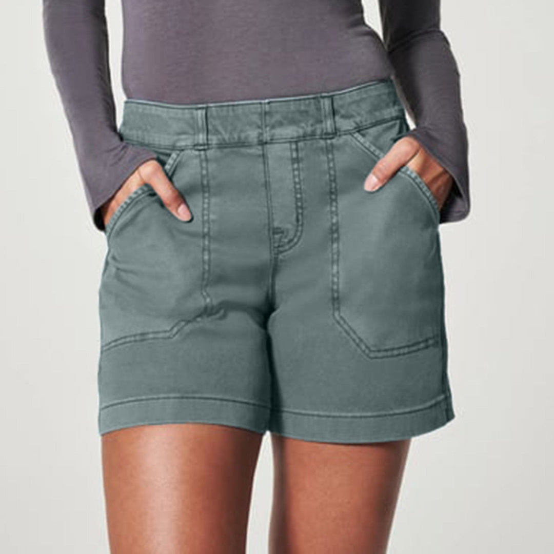 Donna in pantaloncini verdi, tasche frontali, maglia a maniche lunghe grigia. Moda casual, abbigliamento estivo, stile confortevole.