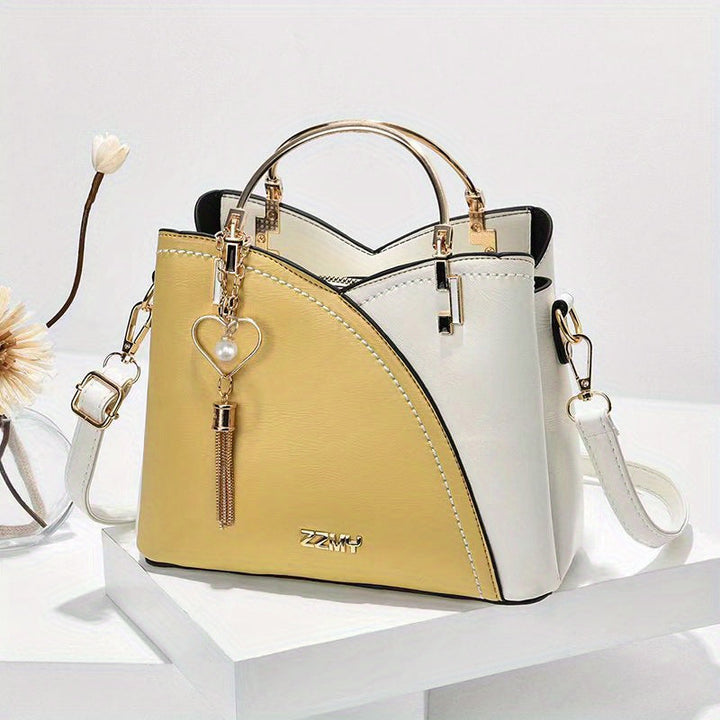 Borsa a mano elegante in pelle bicolore bianca e gialla, con manico dorato e ciondolo a cuore, perfetta per moda femminile e accessori di lusso.