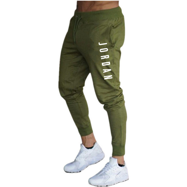 Pantaloni jogger verdi da uomo con scritta "Jordan", stile casual sportivo, abbinati a scarpe bianche. Ideali per attività sportive e tempo libero.