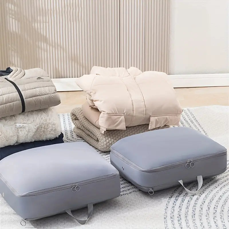 Sacchetti sottovuoto grigi per abbigliamento, giacche e coperte su tappeto. Soluzione salvaspazio per organizzazione e conservazione vestiti.