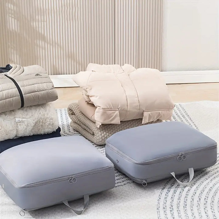 Sacchetti sottovuoto grigi per abbigliamento, giacche e coperte su tappeto. Soluzione salvaspazio per organizzazione e conservazione vestiti.