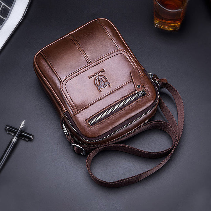 Borsa a tracolla in pelle marrone, design elegante con cerniera frontale e logo, ideale per uomo, accessorio moda, stile casual e pratico.