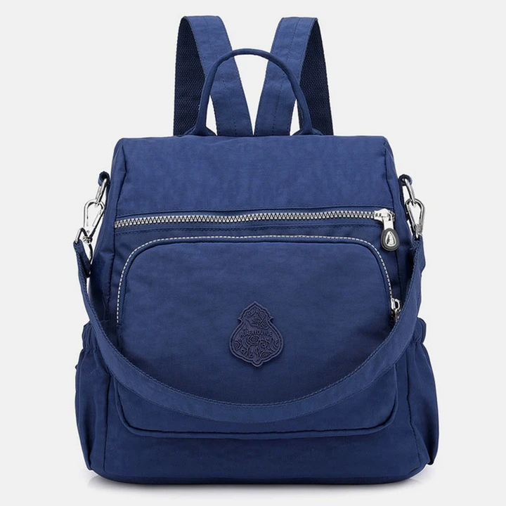Zaino blu in nylon impermeabile con tasca frontale con zip, spallacci regolabili e manico superiore. Design elegante e pratico per viaggi e scuola.