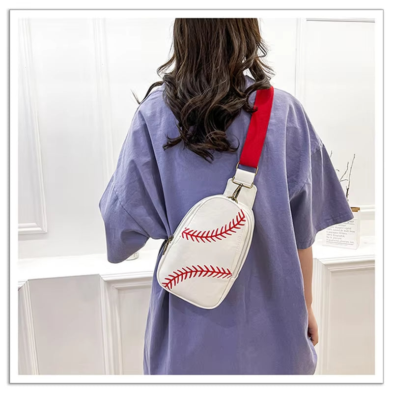 Donna con borsa a tracolla bianca a forma di pallina da baseball, dettagli rossi, tracolla rossa, indossa maglietta viola. Accessorio moda sportivo.