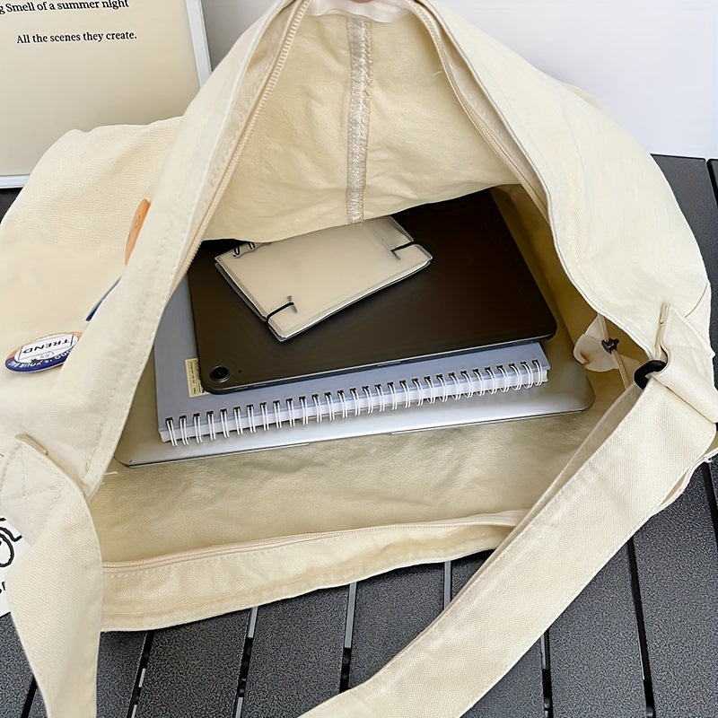 Borsa di tela beige aperta su tavolo, contenente laptop, quaderno a spirale e custodia per smartphone. Accessori per lavoro e studio.