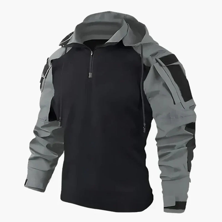 Giacca softshell nera e grigia con cappuccio, zip frontale e tasche multiple. Abbigliamento outdoor impermeabile e antivento per escursionismo.