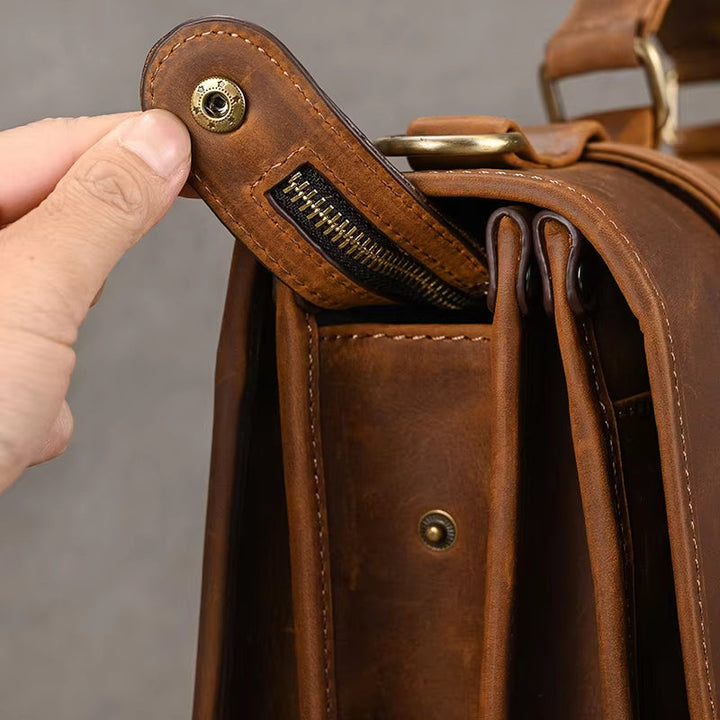 Borsa in pelle marrone con chiusura a bottone e cerniera, design elegante e resistente, ideale per lavoro e viaggio. Accessorio moda uomo.