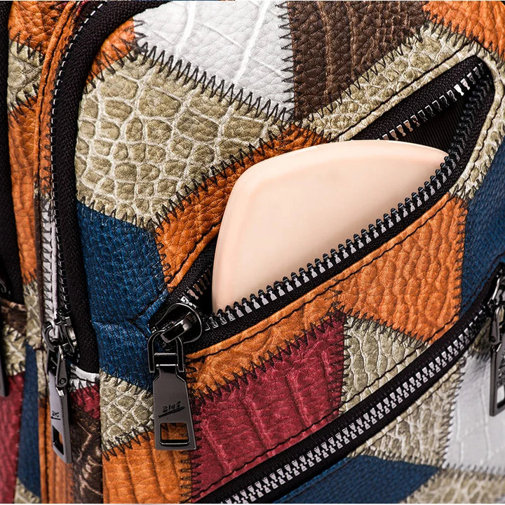 Zaino in pelle patchwork multicolore con tasca aperta, cerniere nere e design geometrico. Accessorio moda unico e trendy.
