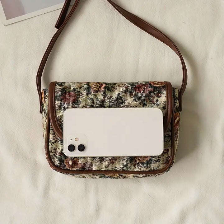 Borsa a tracolla vintage in tessuto floreale con smartphone bianco, design elegante, accessorio moda donna, perfetta per look casual e chic.