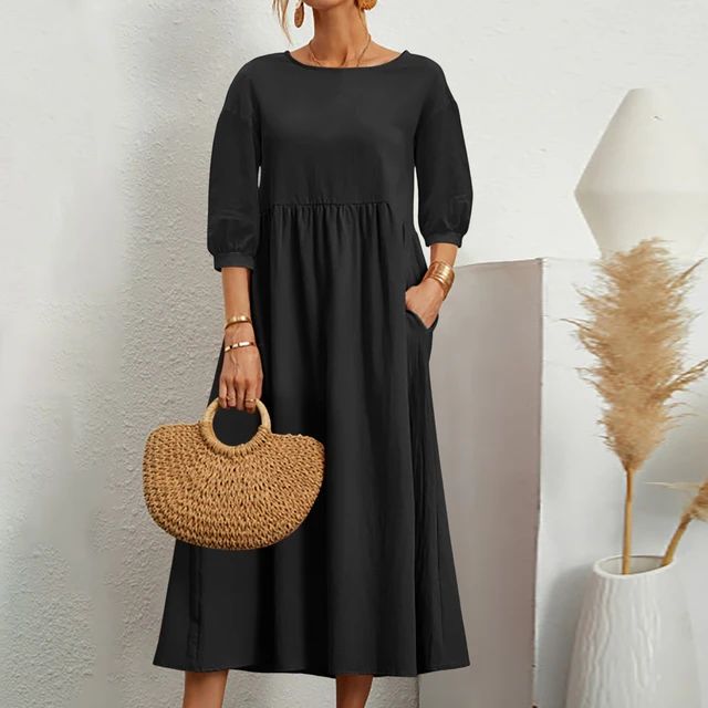 Abito nero lungo donna con maniche a tre quarti, borsa paglia intrecciata, sfondo bianco minimalista, decorazione pampas. Moda elegante casual.