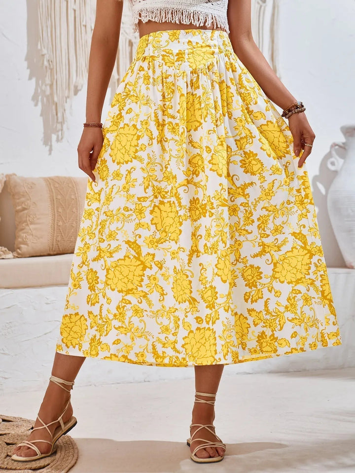 Gonna lunga floreale gialla e bianca, stile boho chic, indossata con sandali estivi. Tessuto leggero, perfetto per la moda estiva femminile.