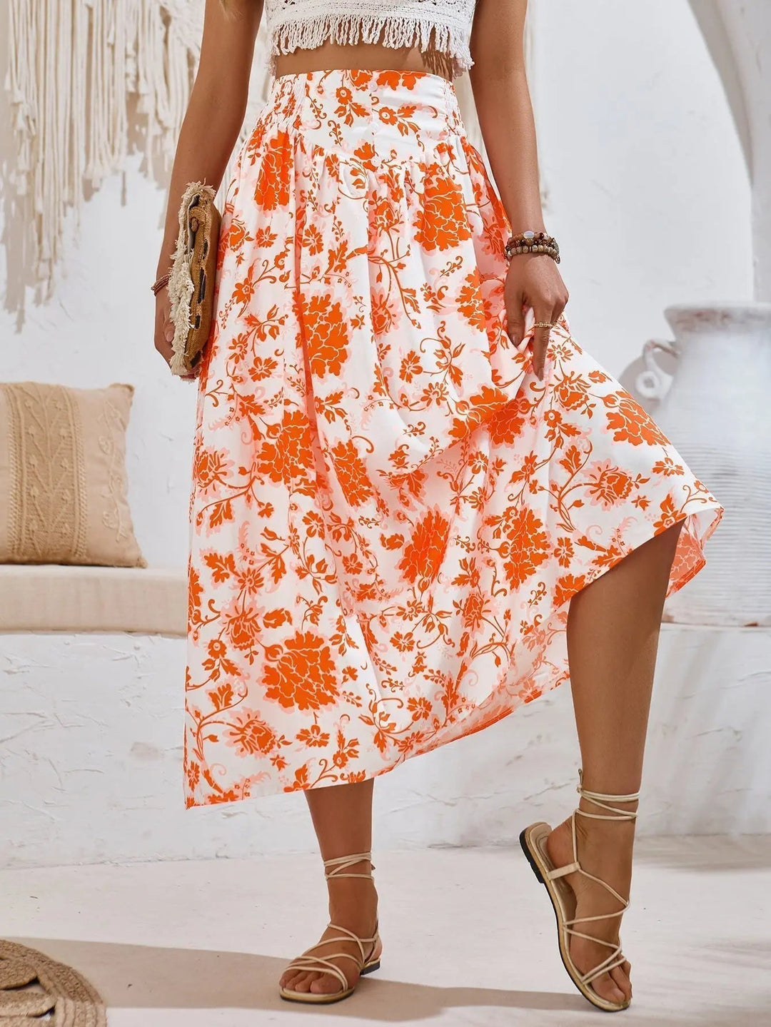 Gonna lunga estiva a fiori arancioni e bianchi, indossata con sandali e top in pizzo. Moda donna boho chic, abbigliamento estivo elegante.
