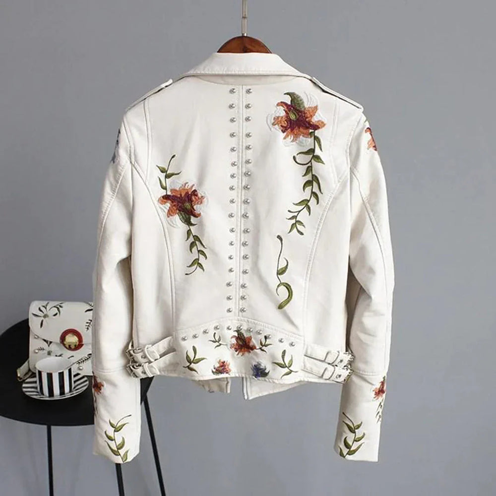 Giacca bianca in pelle con ricami floreali colorati, borchie decorative e cinture regolabili. Moda donna, abbigliamento trendy, stile casual.