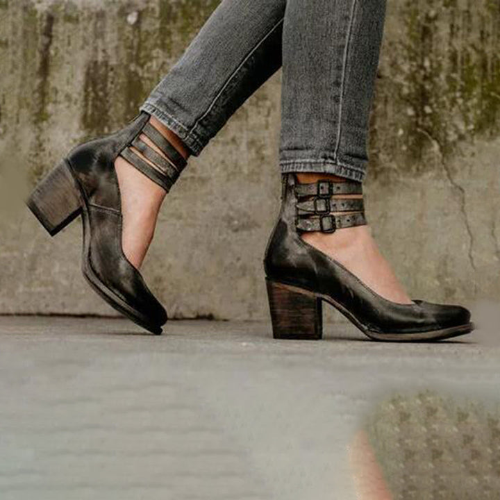 Scarpe donna nere con tacco largo e cinturini multipli, indossate con jeans grigi. Eleganti e versatili, ideali per moda autunno.