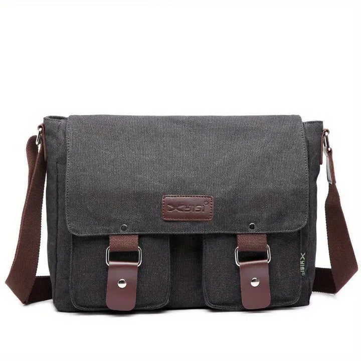 Borsa a tracolla in tela grigia con patta, tasche frontali e dettagli in pelle marrone. Design unisex, ideale per lavoro e tempo libero.