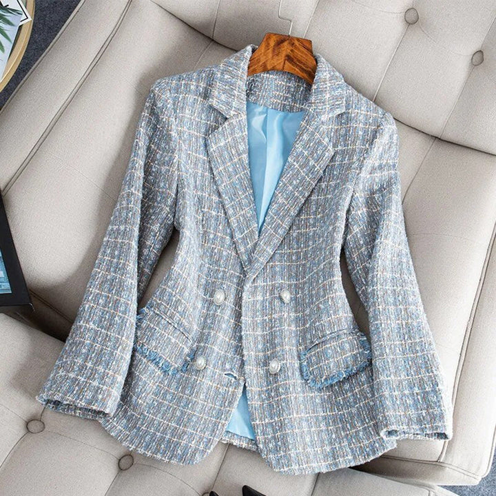 Giacca blazer donna in tweed blu, doppio petto, elegante, su poltrona beige. Moda femminile, abbigliamento formale, stile classico.