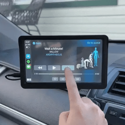 Schermo touchscreen auto con interfaccia musicale, brano in riproduzione "Wait a Minute!" di Willow, icone di controllo visibili.