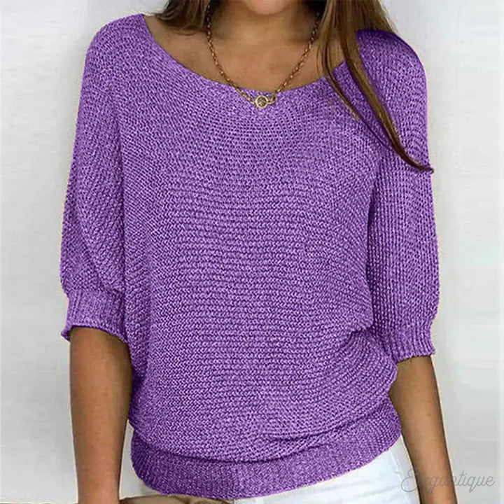 Maglione donna viola a maniche corte, scollo a barca, tessuto lavorato a maglia, indossato con collana dorata. Moda casual elegante.