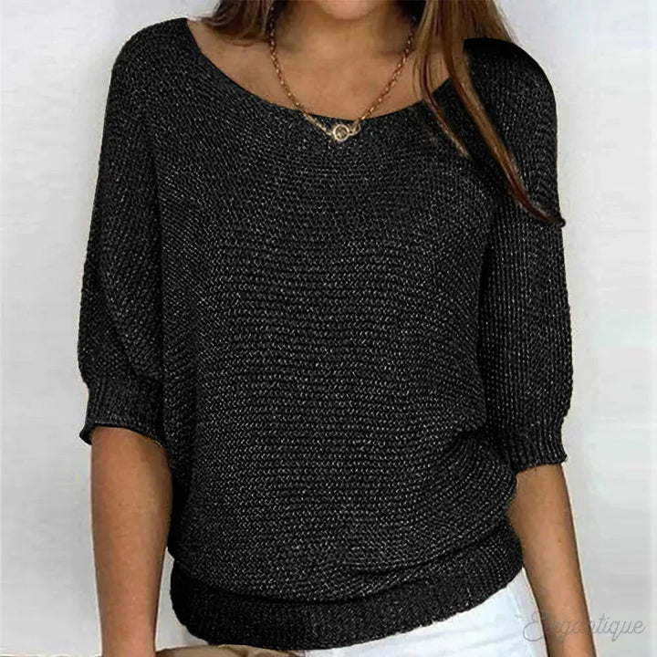 Maglia donna nera a maniche corte, tessuto lavorato a maglia, scollo a barca, abbinata a pantaloni bianchi. Elegante e casual, perfetta per ogni occasione.