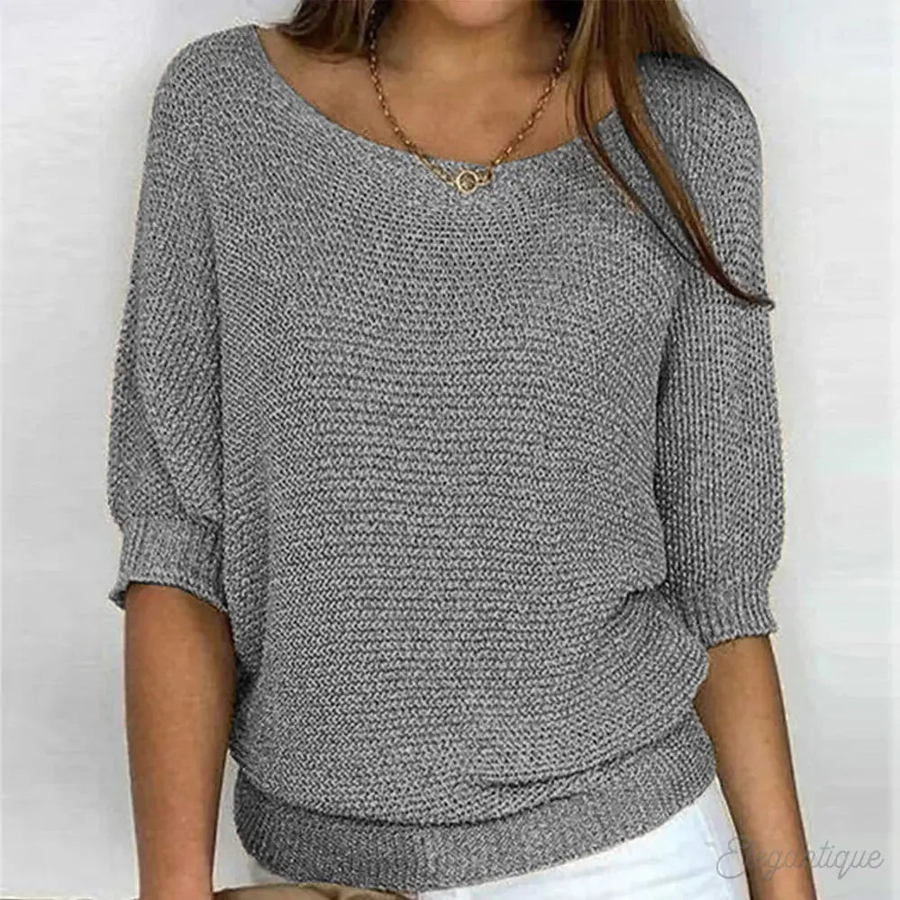 Maglione donna grigio a maniche corte, lavorato a maglia, scollo a barca, indossato con jeans bianchi. Moda casual elegante, abbigliamento autunnale.