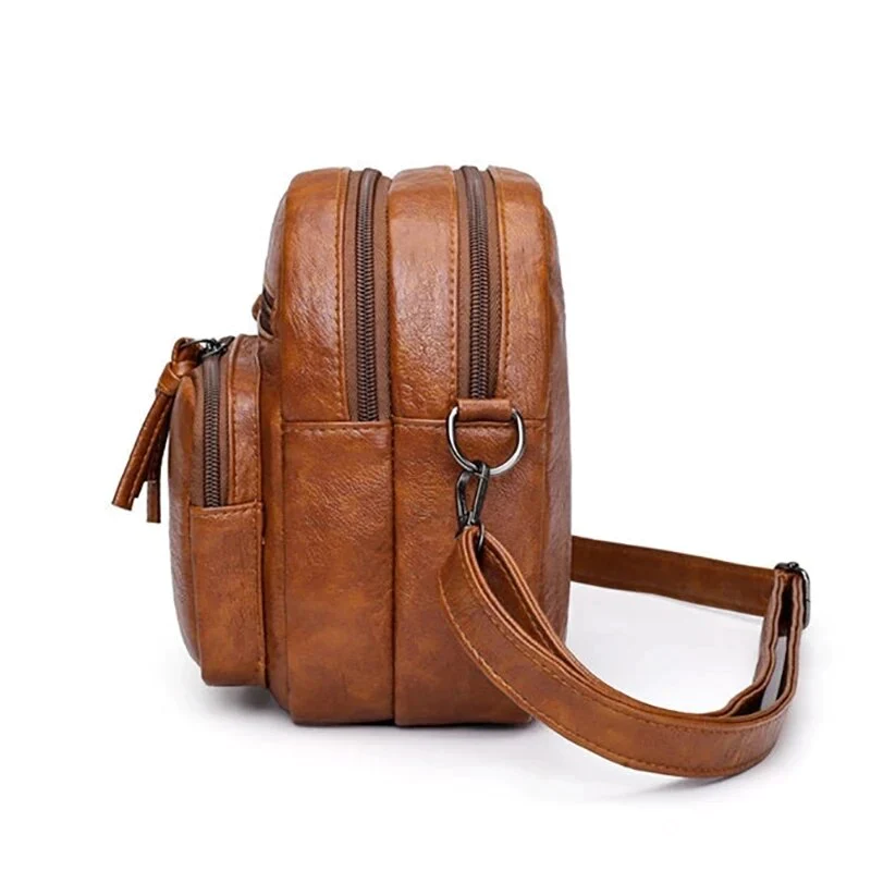 Zaino in pelle marrone con doppia cerniera, tasche multiple e tracolla regolabile. Design elegante e pratico per uomo e donna.