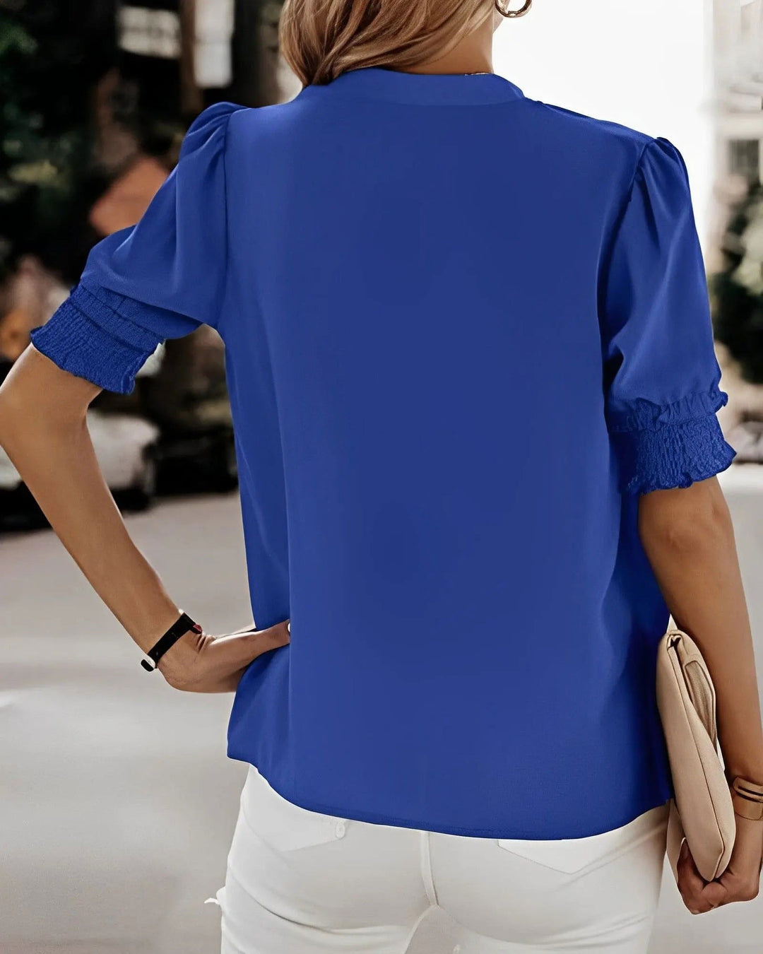 Donna con camicetta blu a maniche corte e pantaloni bianchi, vista posteriore. Moda estiva casual, abbigliamento femminile elegante.