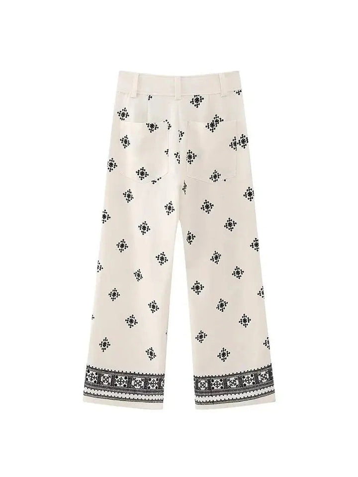 Pantaloni bianchi donna con motivo geometrico nero, taglio ampio, tasche posteriori, orlo decorato. Stile casual elegante.