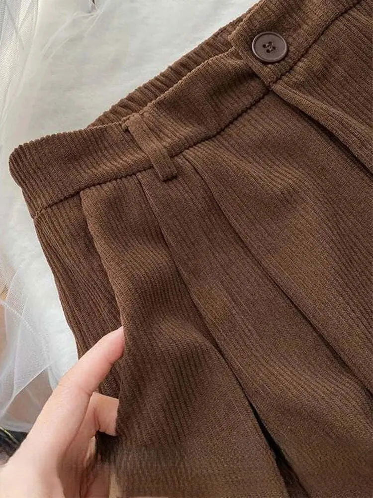 Pantaloni marroni a vita alta in tessuto a coste, con cintura elastica e bottone. Design elegante e versatile per moda autunnale.