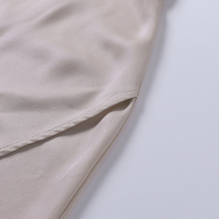 Camicia beige in seta, dettaglio del tessuto morbido e lucido, cuciture precise. Elegante e raffinata, ideale per abbigliamento formale.