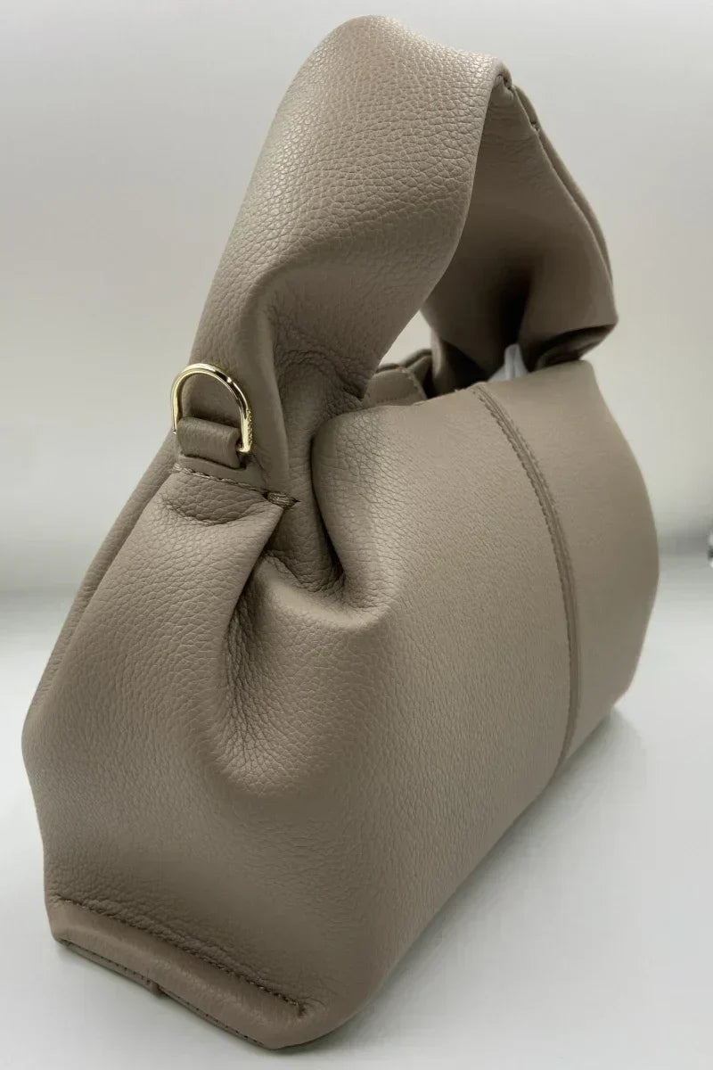 Borsa a mano in pelle beige, design elegante con manico morbido e dettagli in metallo dorato. Accessorio moda donna, stile contemporaneo.