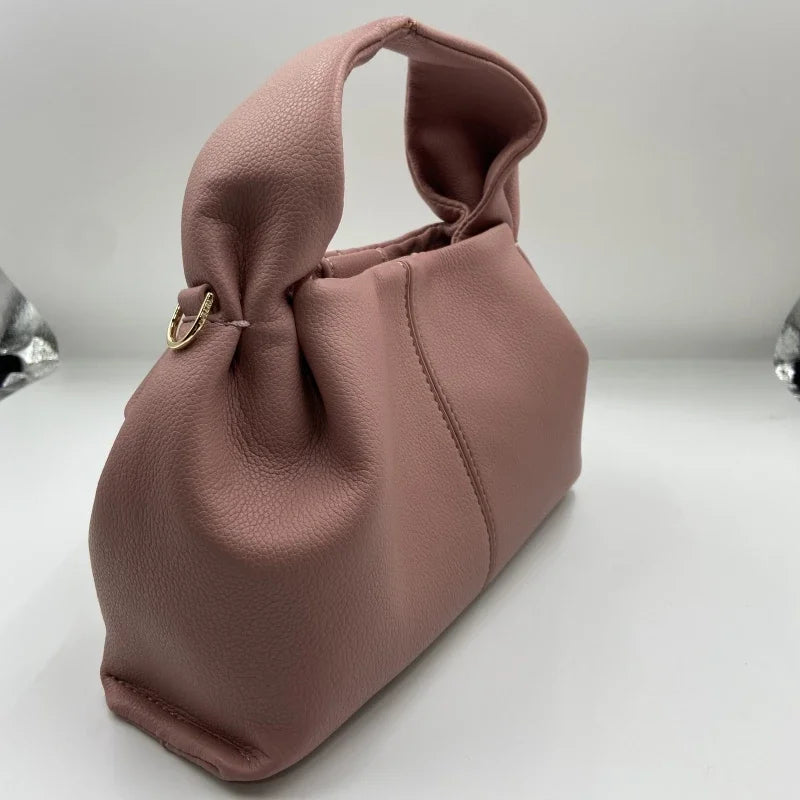 Borsa a mano in pelle rosa, design elegante con manico morbido e chiusura a fibbia dorata. Accessorio moda donna, stile contemporaneo.