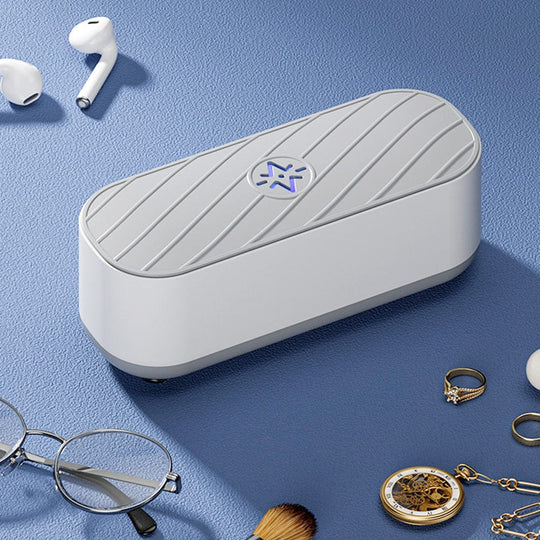 Sterilizzatore UV portatile bianco su tavolo blu, circondato da occhiali, anelli, orologio e auricolari. Dispositivo igienizzante per oggetti personali.