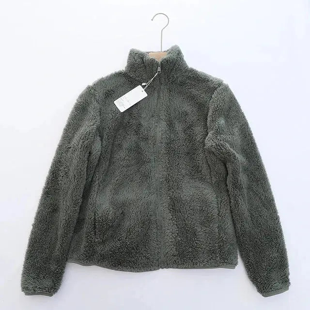 Giacca in pile grigio scuro, morbida e calda, con zip frontale e etichetta, appesa su gruccia. Ideale per l'inverno e attività all'aperto.