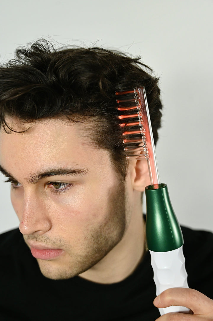Uomo utilizza pettine elettrico per capelli su sfondo bianco. Strumento per cura capelli, styling maschile, tecnologia bellezza.