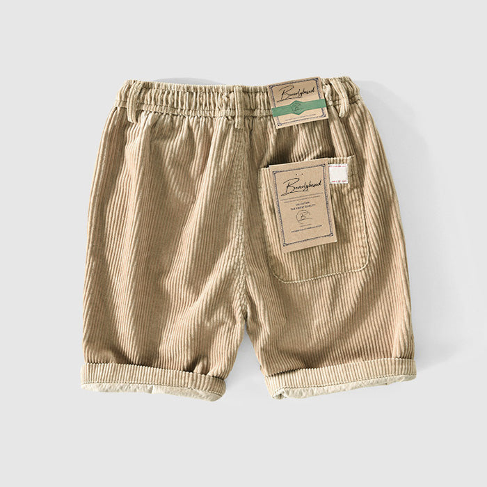 Pantaloncini bambino in velluto a coste beige, elastico in vita, tasca posteriore, etichette brand. Abbigliamento estivo casual per bambini.