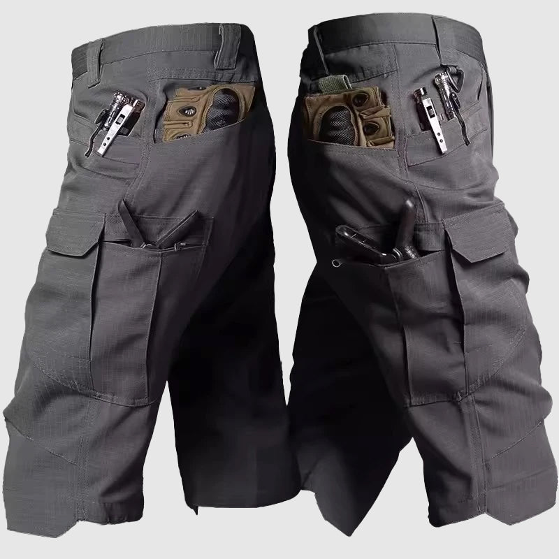 Pantaloncini tattici grigi con tasche multiple, design resistente, ideali per attività all'aperto. Tasche con cerniera e scomparti per accessori.