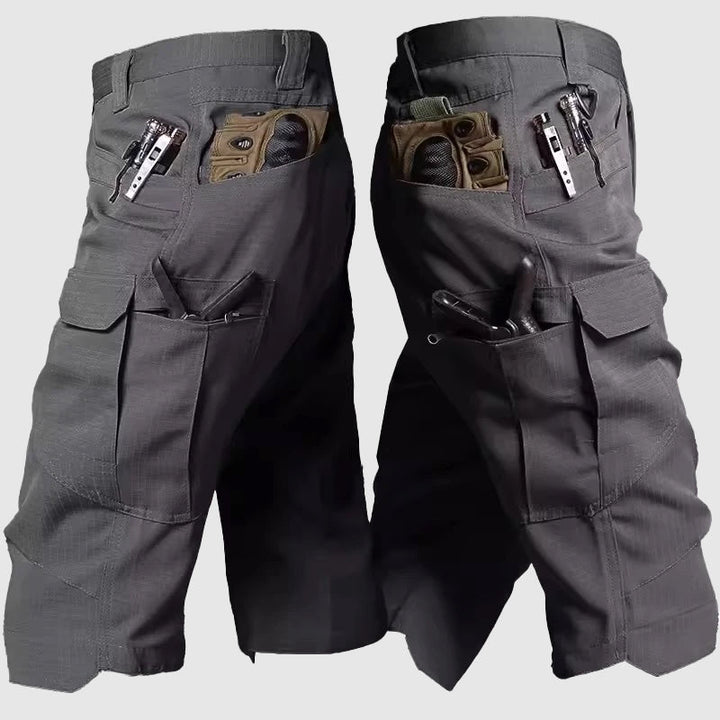 Pantaloncini tattici grigi con tasche multiple, design resistente, ideali per attività all'aperto. Tasche con cerniera e scomparti per accessori.