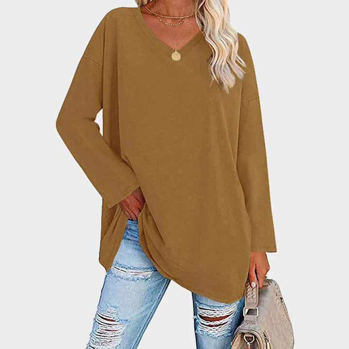 Maglia oversize marrone da donna con scollo a V, abbinata a jeans strappati e borsa beige. Look casual e alla moda per l'autunno.