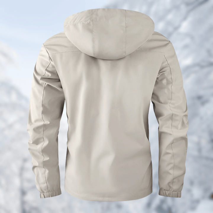 Giacca impermeabile beige con cappuccio, vista posteriore, su sfondo invernale. Abbigliamento outdoor, antivento, ideale per escursioni e sport invernali.