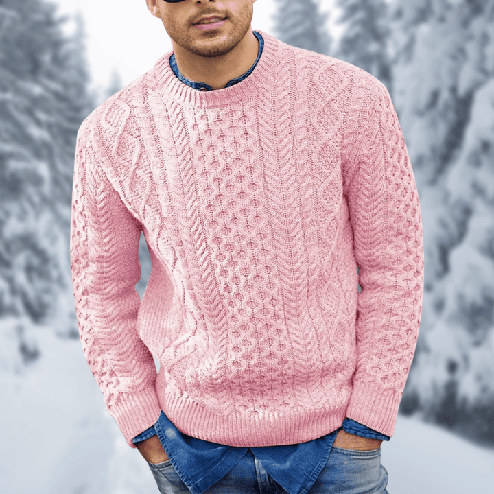 Maglione rosa in lana a trecce per uomo, indossato sopra camicia di jeans, sfondo invernale con alberi innevati. Moda maschile, abbigliamento caldo.