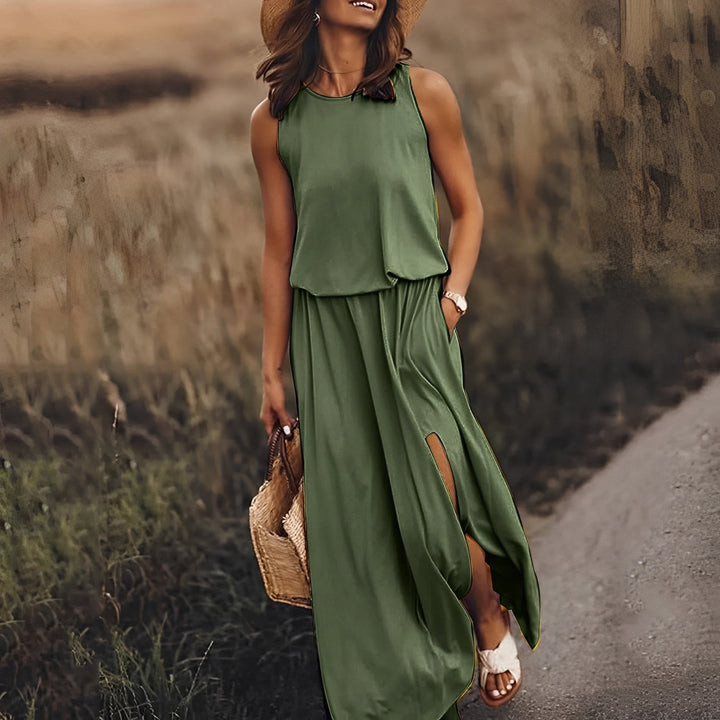Donna con abito lungo verde estivo, cappello di paglia e borsa intrecciata, cammina su un sentiero. Moda estiva, abbigliamento casual elegante.
