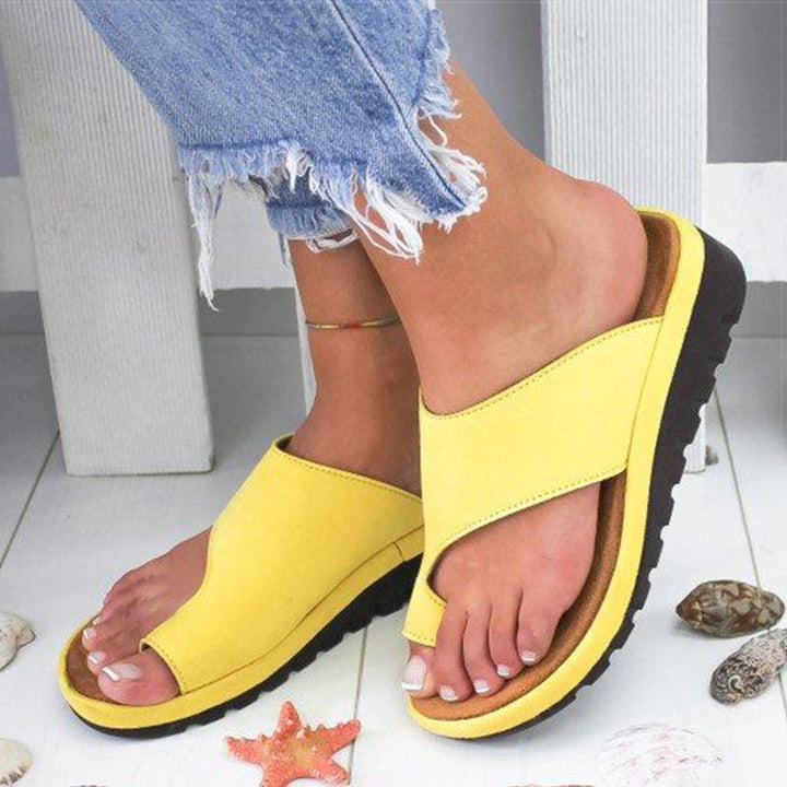 Sandali gialli da donna con suola nera, indossati con jeans strappati. Design estivo, comodi e alla moda, perfetti per la spiaggia.