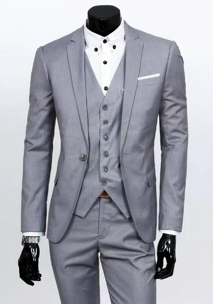 Abito elegante da uomo grigio chiaro, tre pezzi, con giacca, gilet e pantaloni coordinati, camicia bianca a bottoni, ideale per cerimonie e matrimoni.