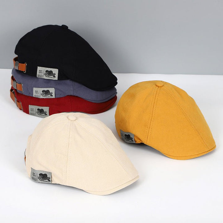 Cappelli piatti in cotone multicolore, stile vintage, con etichetta, disponibili in nero, rosso, grigio, giallo e beige. Accessori moda uomo.
