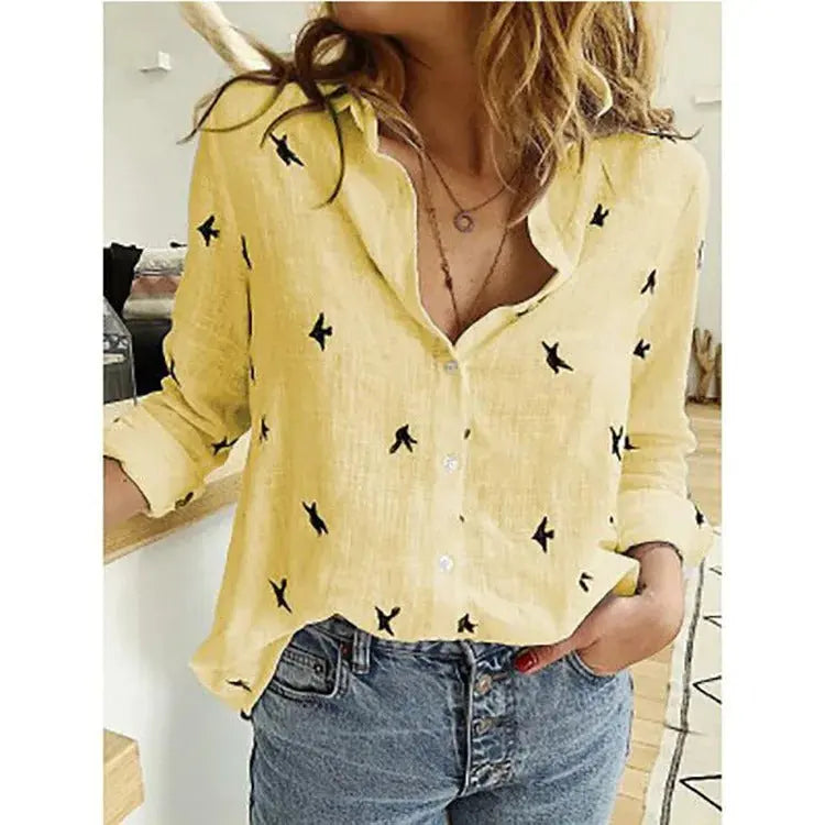 Camicia gialla donna con motivo uccelli neri, maniche lunghe arrotolate, abbinata a jeans blu. Stile casual, moda femminile, abbigliamento estivo.