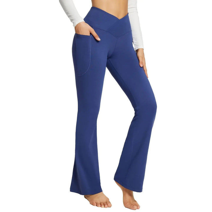 Pantaloni yoga blu a vita alta con tasche, design a campana, indossati da una donna. Abbigliamento sportivo comodo ed elegante per fitness e tempo libero.